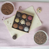 ask med 9 brigadeiros med olika typer av strössel med en skål av kakao nibs och en skål av Crispearls